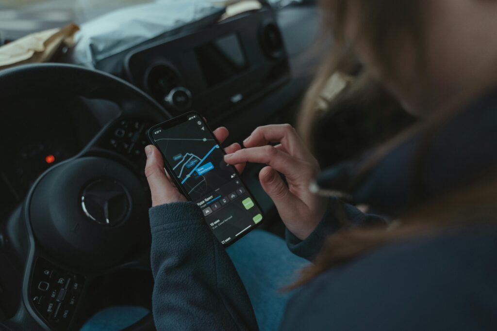 Person using GPS navigation app on smartphone inside car for directions.